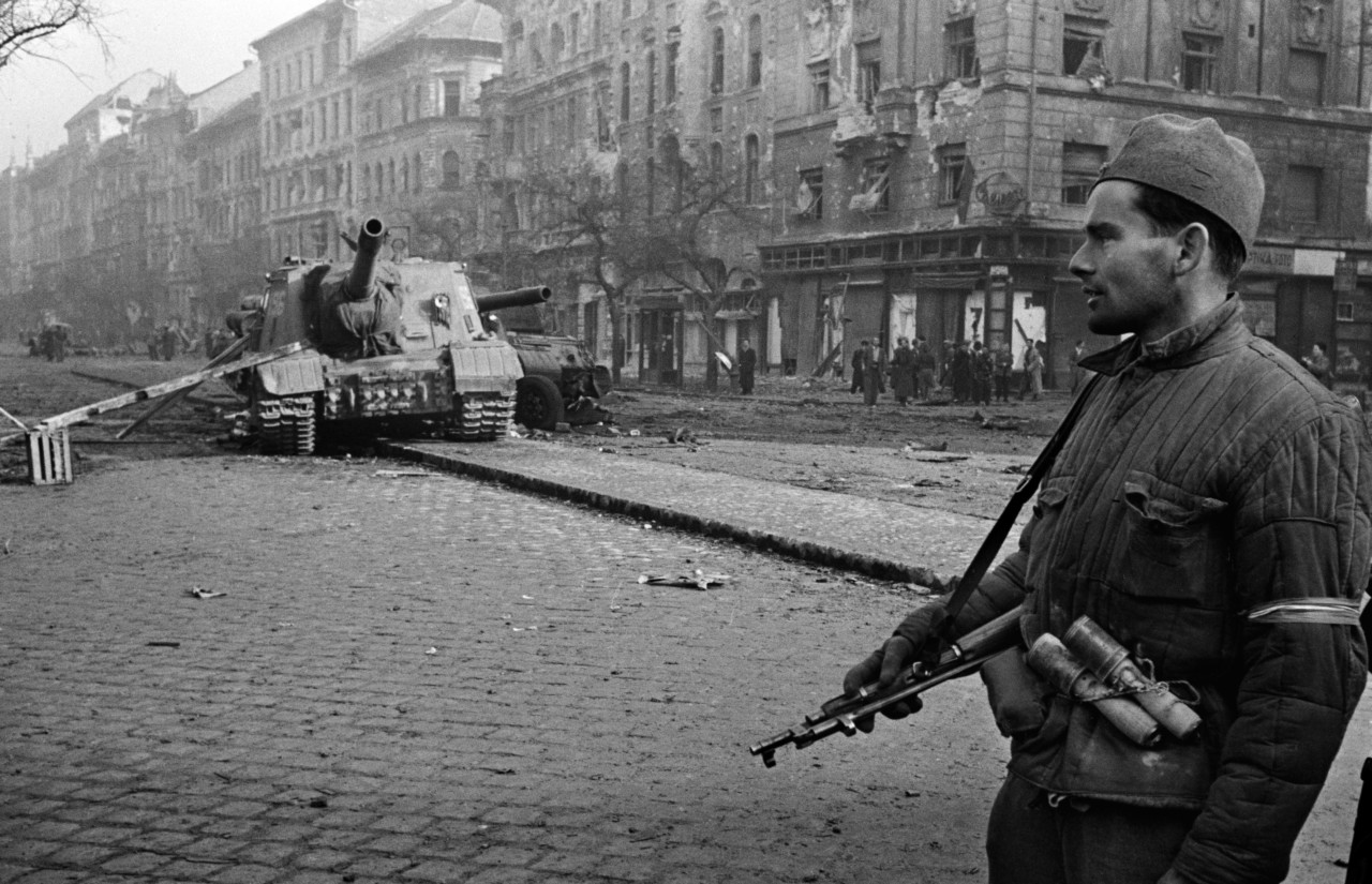 Man with gun, tank in background